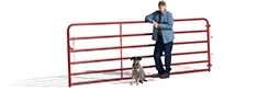 Profile of a man leaning against a red fence with his dog sitting next to him.